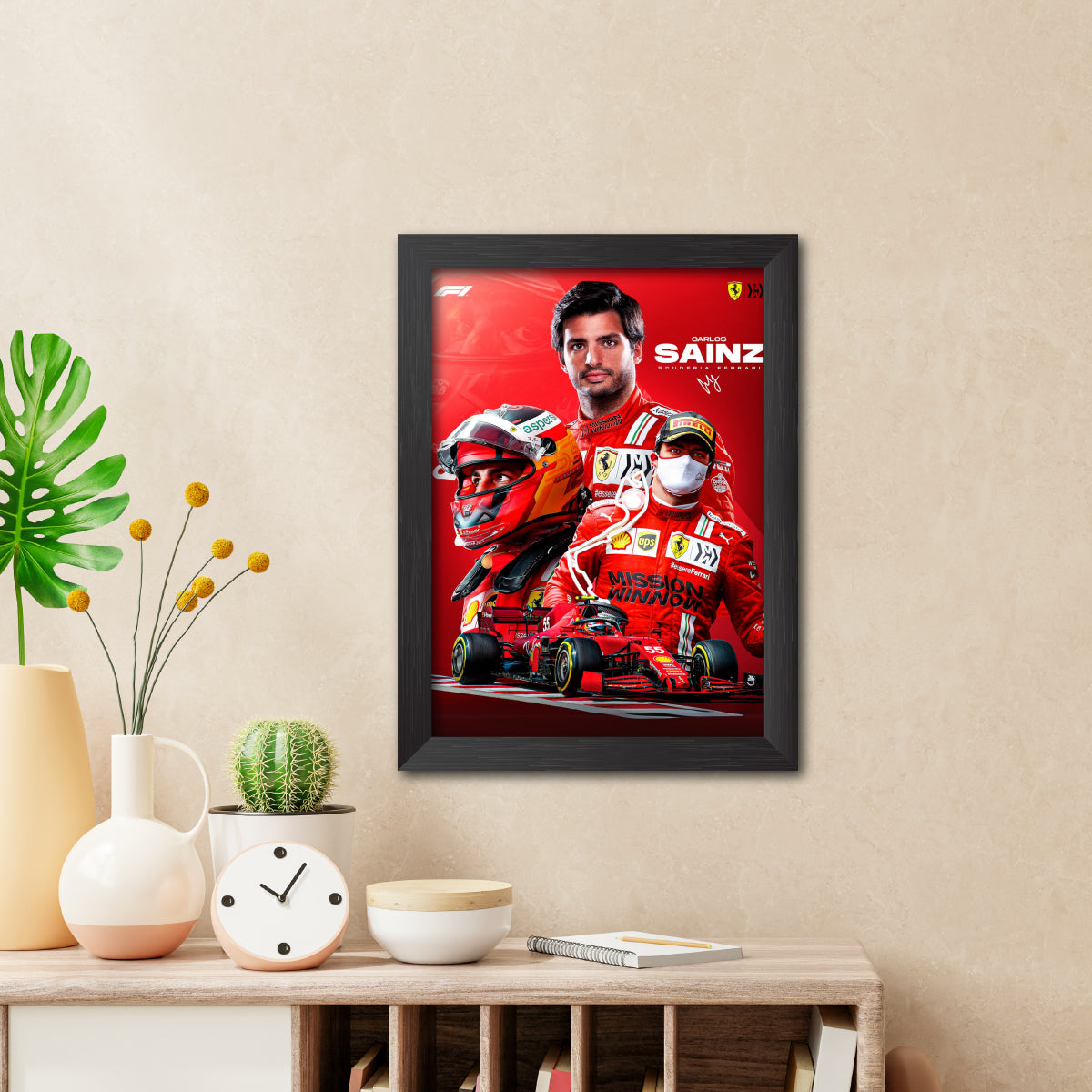 Framed poster of a Formula 1 driver on a wall above a wooden shelf with decorative items.