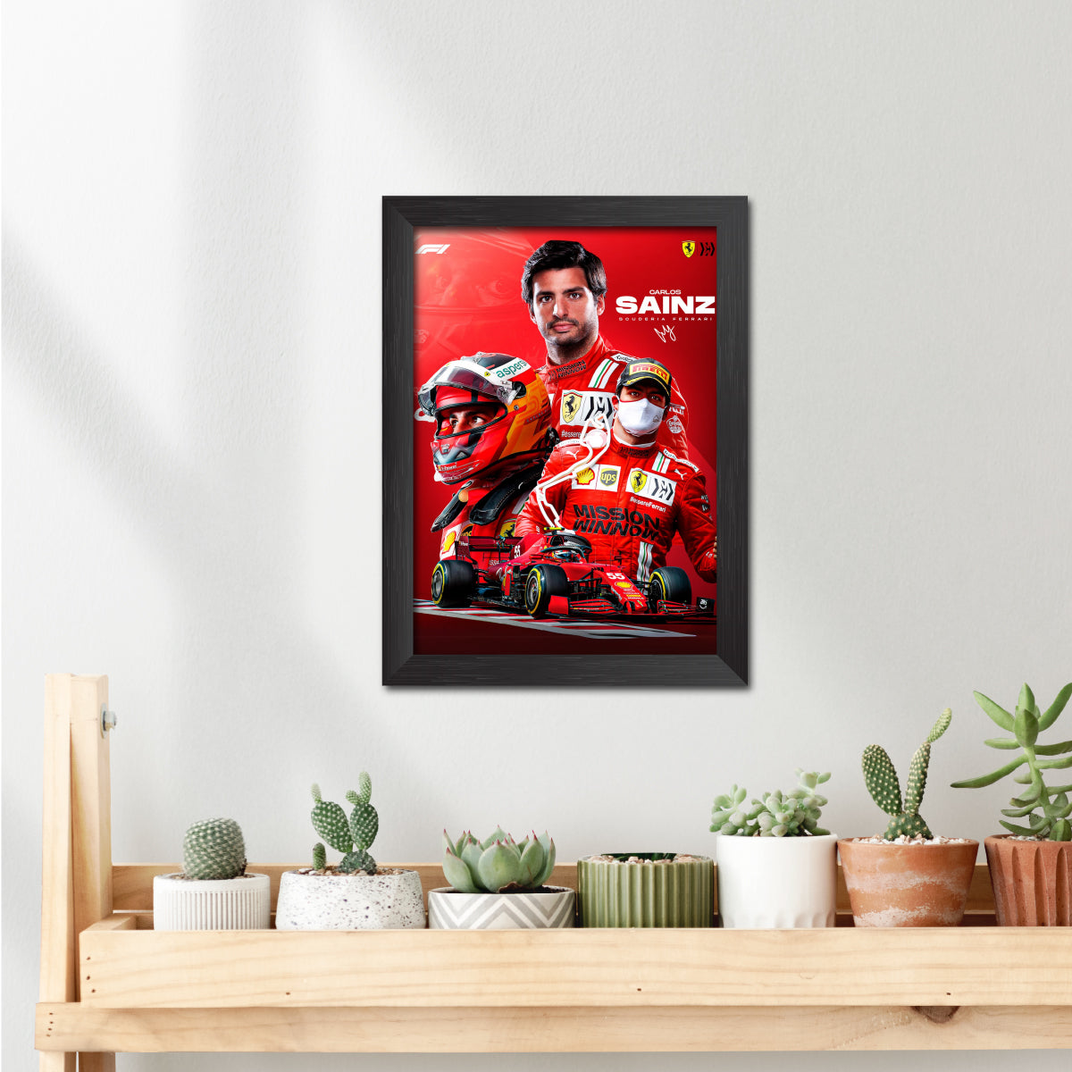 Framed poster of a Formula 1 driver with a red car on a white wall above a wooden shelf with plants.